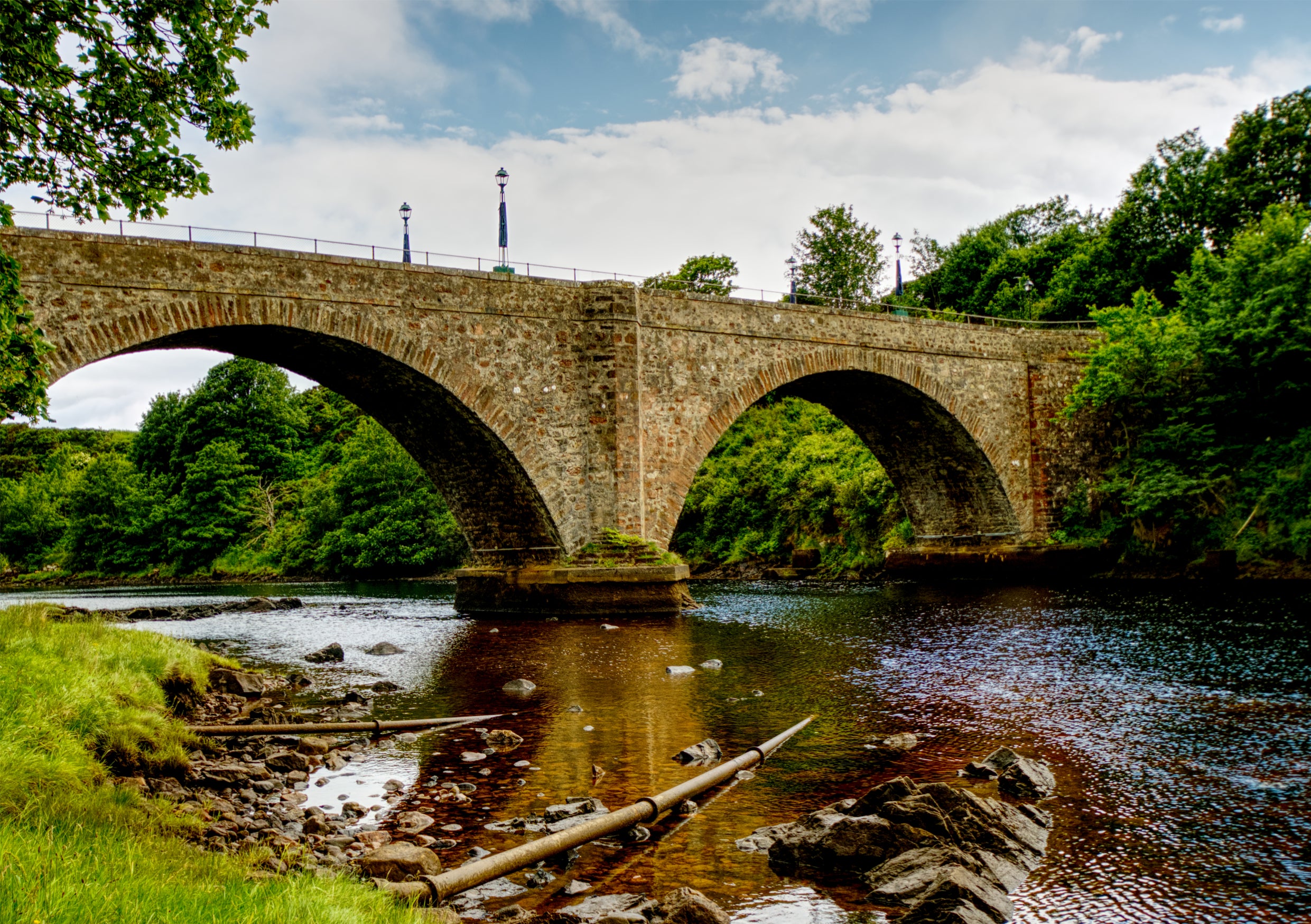 Fine Art Print der historischen zweibogigen Steinbruecke Helmsdale Bridge von Thomas Telford in Sutherland, Schottland, mit einer Spiegelung im gold leuchtenden Flusslauf
